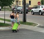 Users cross a street with green shopping trolley